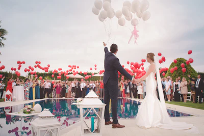 Maya and Jonah releasing white balloons over a pool as their guests cheer