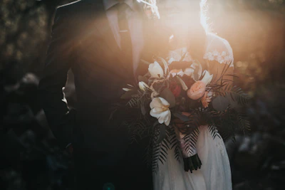 Backlit bridal bouquet of magnolias and peach roses at golden hour
