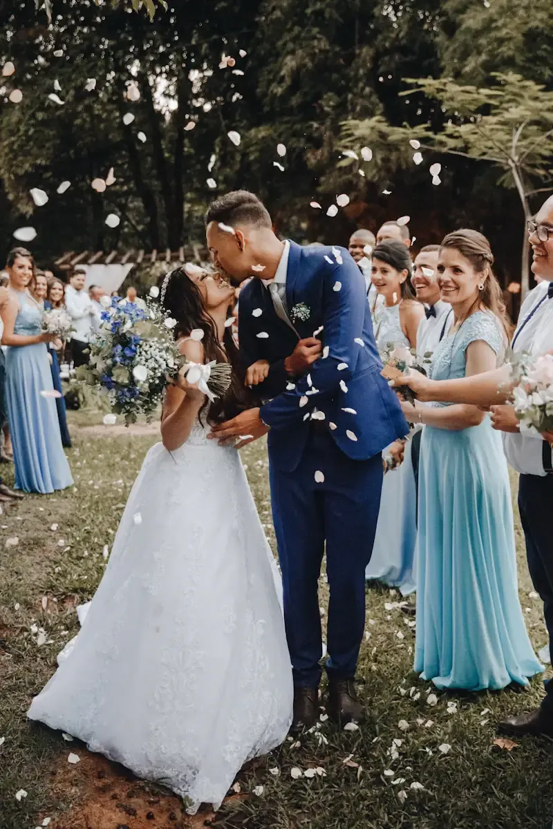 Couple kissing in a shower of flower petals thrown by their wedding party