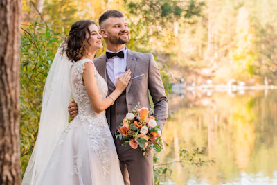 Claire and Théo embracing beside a calm lake ringed with autumn trees