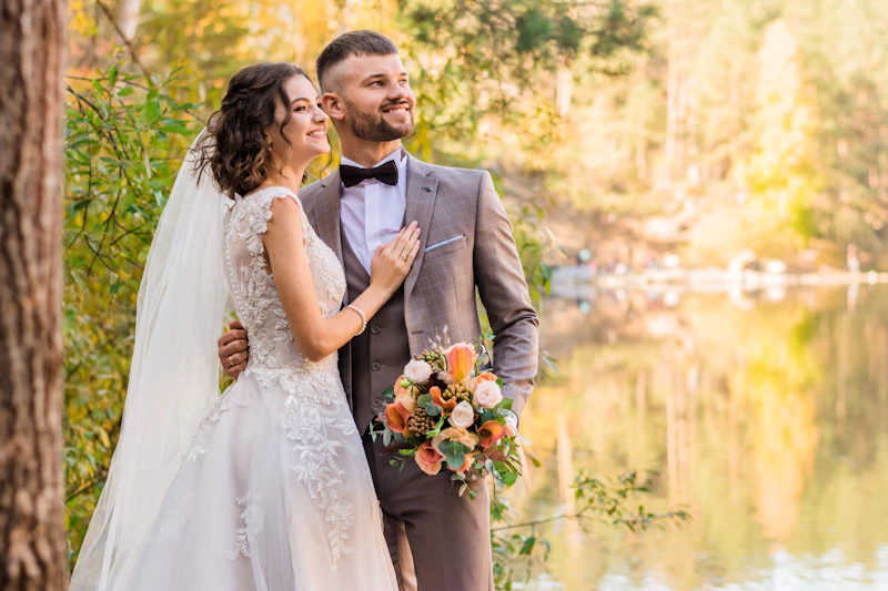 Couple embracing beside a calm lake ringed with autumn trees